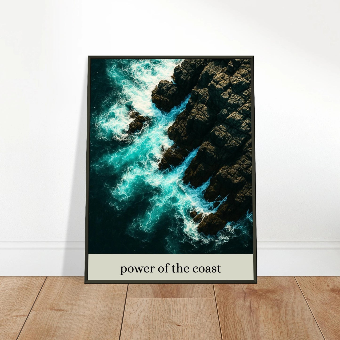Power of the Coast Poster an die Wand gelehnt – moderne Meereskunst mit schwarzem Metallrahmen auf Holzuntergrund.